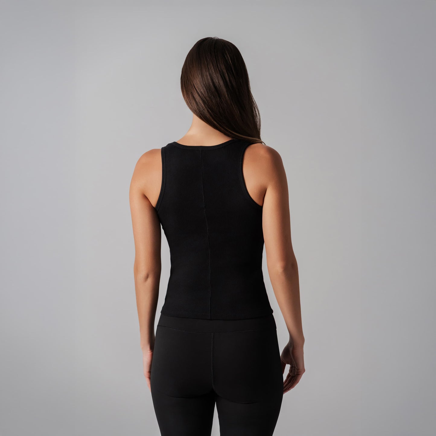 Person wearing a black sleeveless top and pants on a gray background