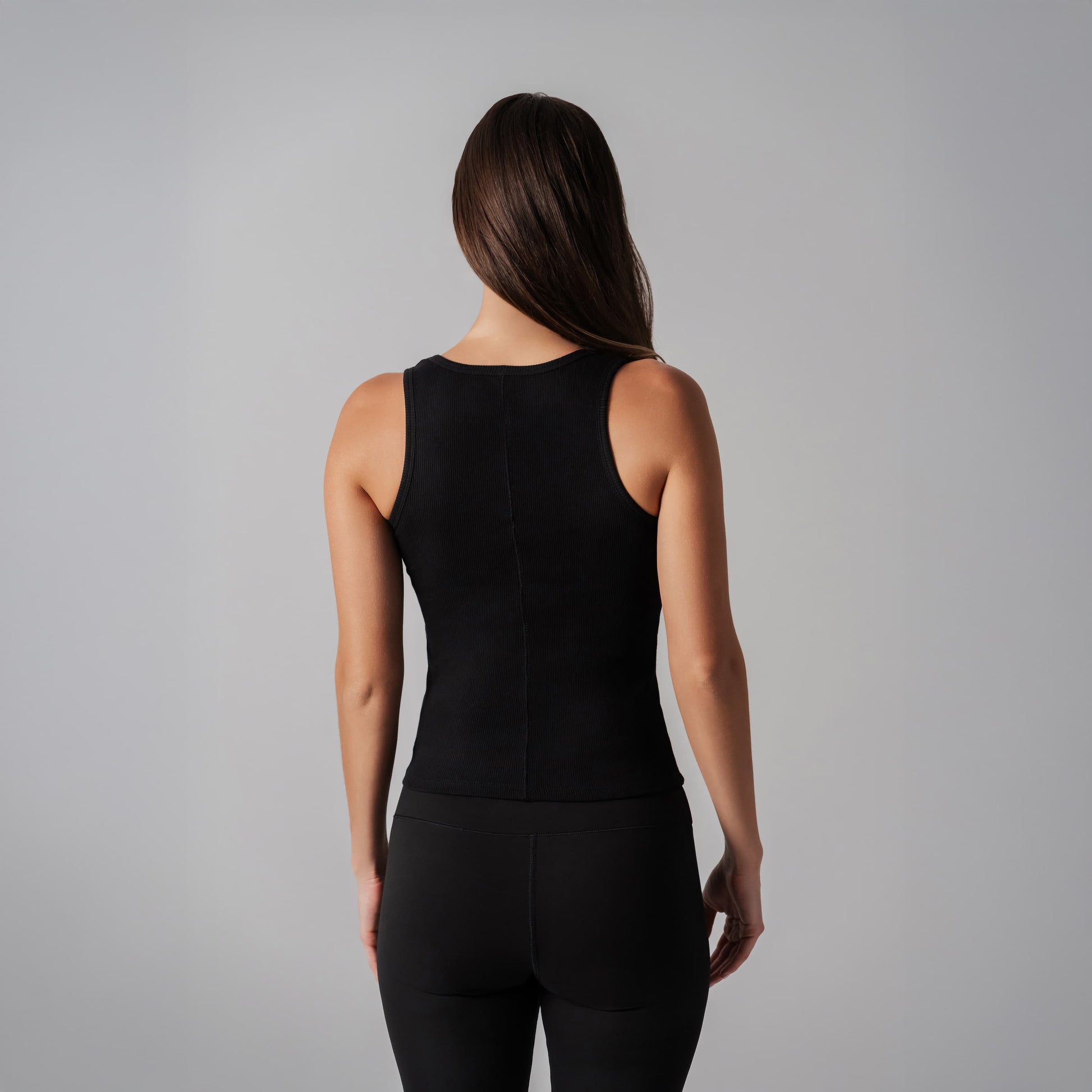 Person wearing a black sleeveless top and pants on a gray background