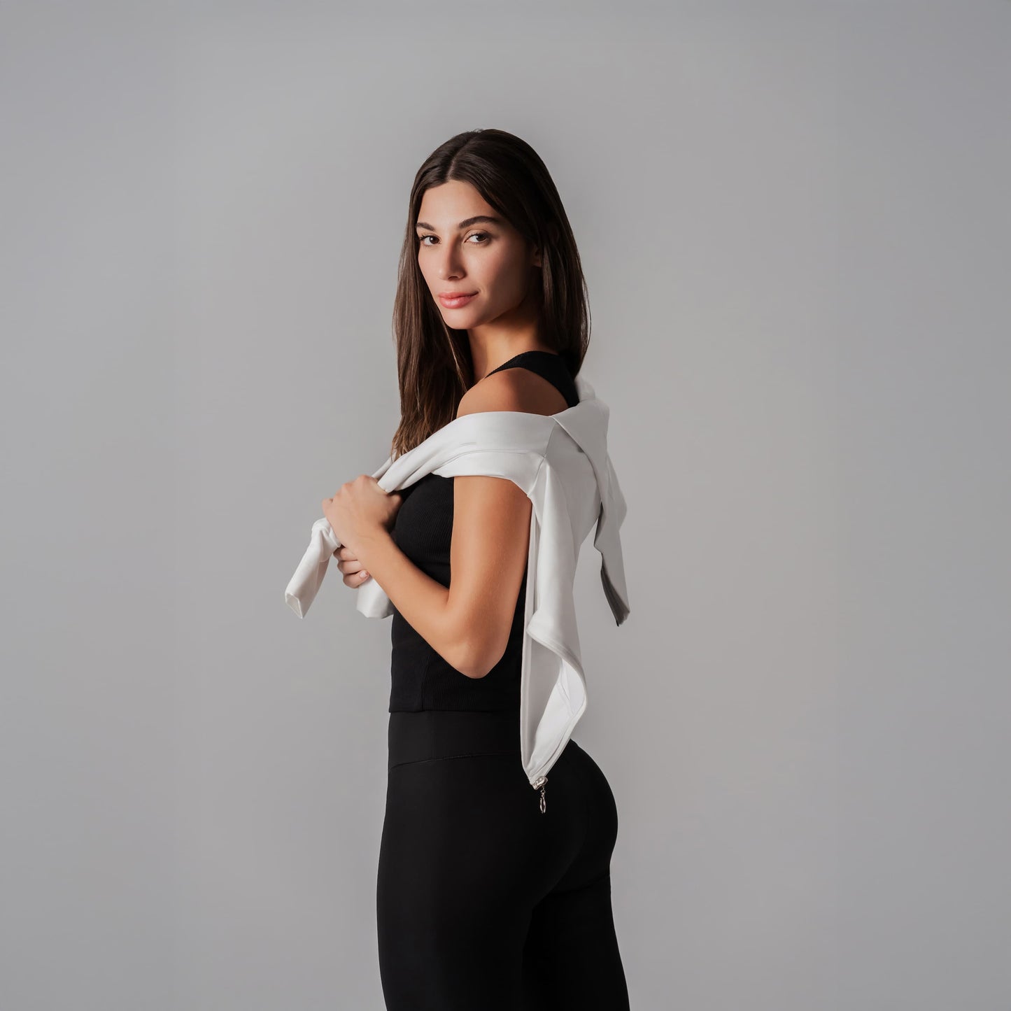 Woman holding a white jacket against a gray background