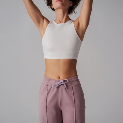 Person wearing a white crop top and pink pants against a gray background