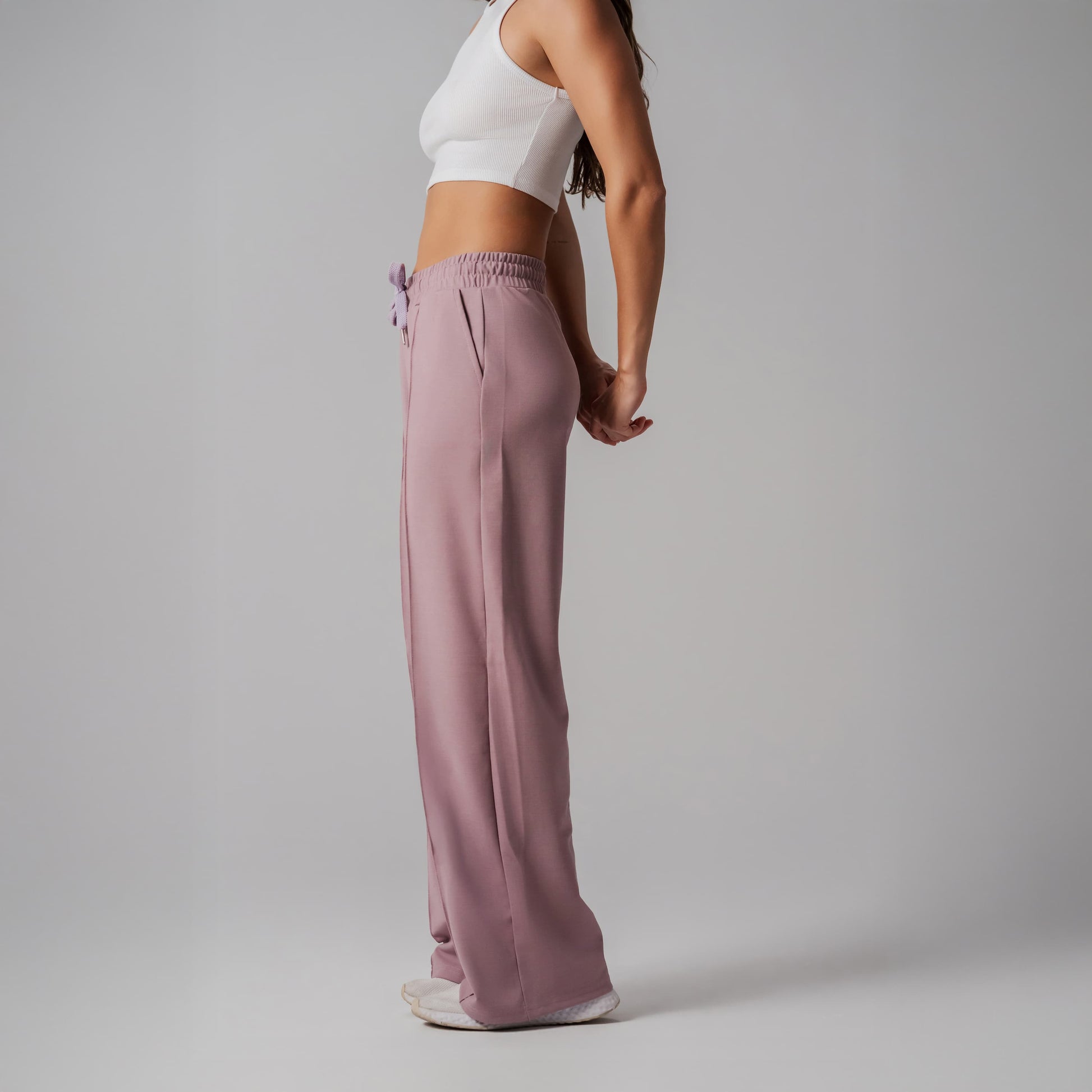 Person wearing a white top and pink pants on a plain background