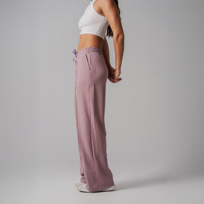 Person wearing a white top and pink pants on a plain background