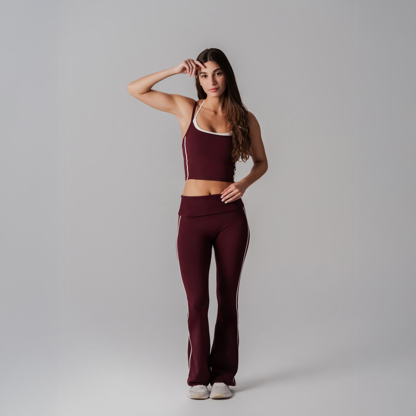Woman wearing a burgundy athletic outfit with white accents on a gray background