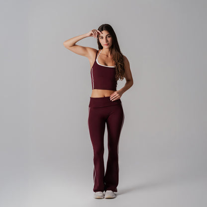 Woman wearing a burgundy athletic outfit with white accents on a gray background