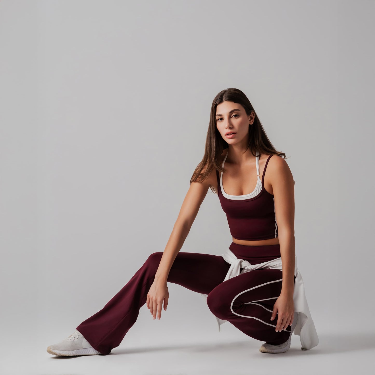 Woman in burgundy athletic outfit posing on a gray background